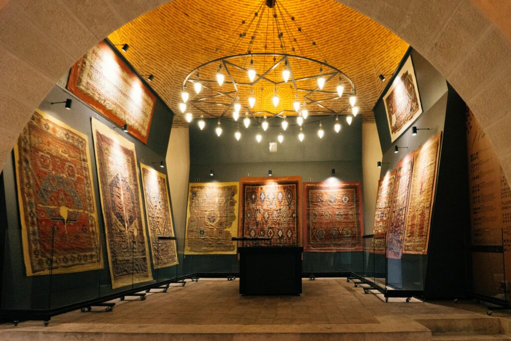 Exquisite display of historic rugs in a well-lit interior archway gallery, showcasing intricate patterns and warm ambiance.
